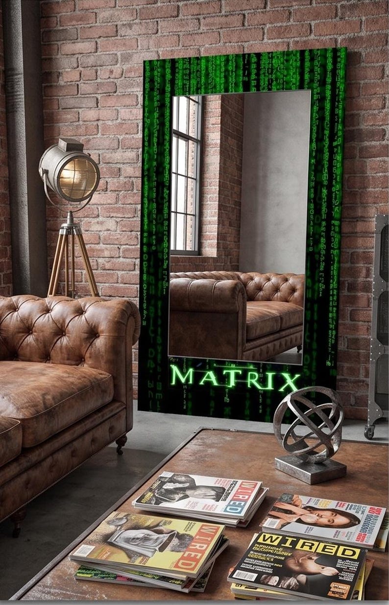 K&ouml;nnte beinhalten: Ein rechteckiger Standspiegel mit einem schwarzen Rahmen, der mit einem gr&uuml;nen digitalen Codemuster verziert ist und unten das Wort MATRIX in leuchtend gr&uuml;nen Buchstaben tr&auml;gt. Die Spiegelfl&auml;che reflektiert ein braunes Ledersofa in einem Raum.