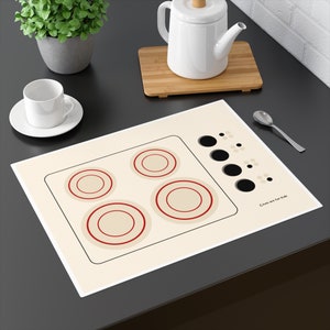 May include: A white play stovetop with four red and cream coloured burner rings and a black and white graphic of a stovetop with knobs. The text "Cooks are for Kids" is printed on the bottom right corner.