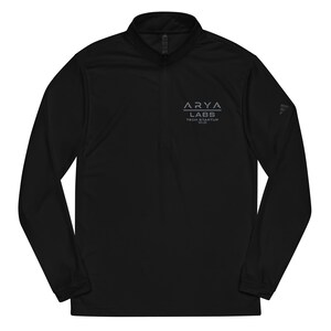 May include: Black long-sleeved athletic top with a quarter-zip collar. The shirt displays the text "ARYA LABS TECH STARTUP V.I.O." in grey on the chest and a small logo on the sleeve.