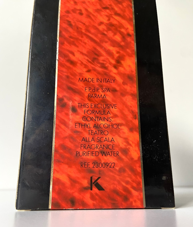 Pu&ograve; includere: Una scatola rossa con bordi dorati e lettere nere. La scatola contiene una bottiglia di profumo. Il testo sulla scatola recita "Made in Italy", "F.P.d P. SPA PARMA", "This exclusive formula contains: Ethyl Alcohol Teatro Alla Scala Fragrance Purified Water", e "REF. 2300922".