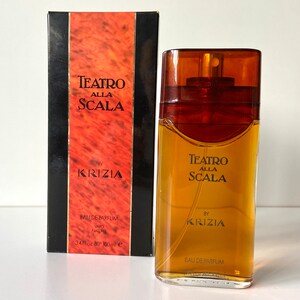 Pu&ograve; includere: Un flacone di profumo Teatro Alla Scala di Krizia in vetro marrone. Il flacone &egrave; rettangolare con un'etichetta dorata e un tappo dorato. La scatola &egrave; rossa e nera con lo stesso testo e logo.