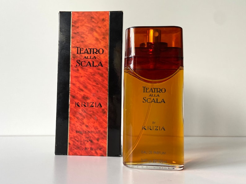 Pu&ograve; includere: Un flacone di profumo Teatro Alla Scala di Krizia in vetro marrone. Il flacone &egrave; da 100 ml e ha un'etichetta dorata con il nome del marchio e il nome del prodotto.