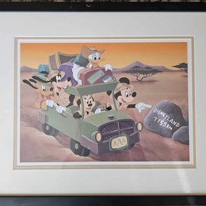 Puede incluir: Una ilustración de dibujos animados vintage de Mickey Mouse, Minnie Mouse, Goofy, Pluto y Donald Duck en un jeep verde conduciendo por un paisaje desértico. El jeep tiene una placa de matrícula que dice "AAA" y un letrero en una roca dice "Disneyland 7155km".