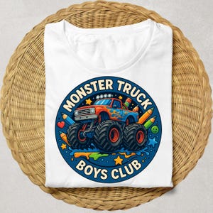 Puede incluir: Camiseta blanca con un dise&ntilde;o de cami&oacute;n monstruo rojo y azul, con llamas y neum&aacute;ticos grandes. El texto "MONSTER TRUCK BOYS CLUB" est&aacute; en un c&iacute;rculo azul, con l&aacute;pices y estrellas.