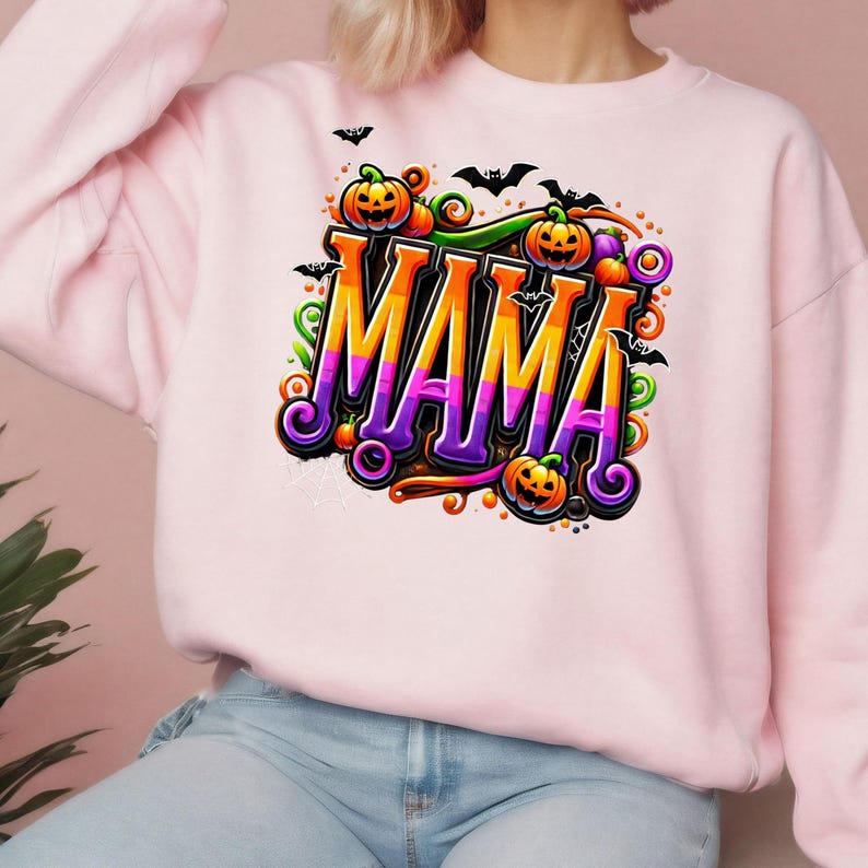 Puede incluir: Sudadera rosa claro con la palabra "MAMA" en letras coloridas, adornada con calabazas, murci&eacute;lagos y remolinos, con tem&aacute;tica de Halloween.