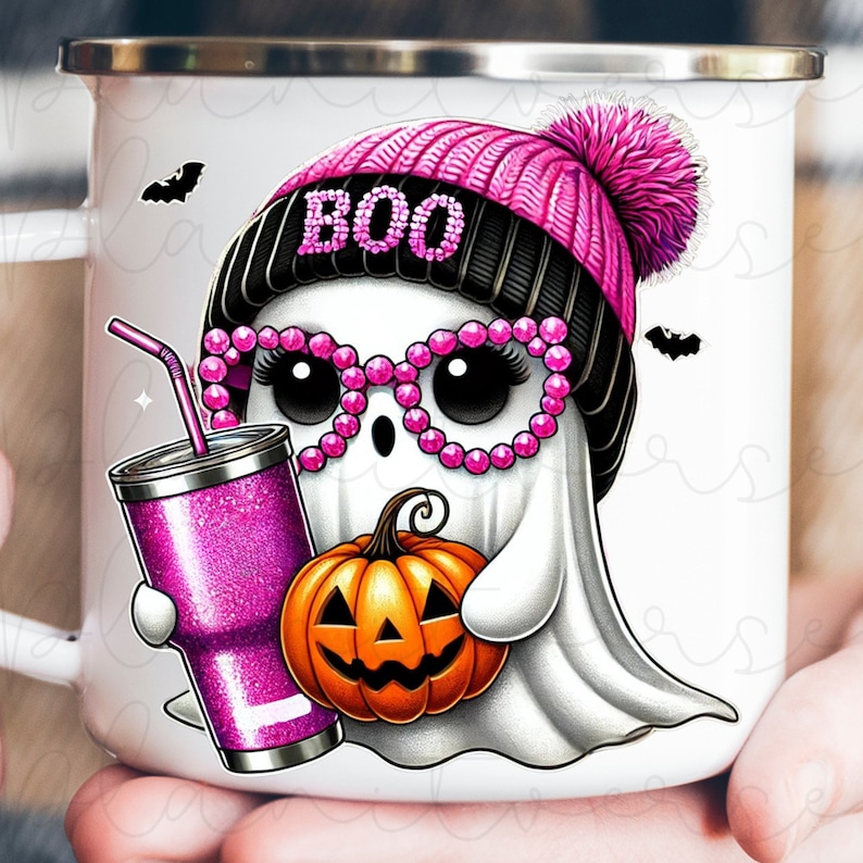 K&ouml;nnte beinhalten: Wei&szlig;e Keramiktasse mit einem rosa und schwarzen Geist, der eine rosa M&uuml;tze mit Bommel und rosa Strasssteinen tr&auml;gt. Der Geist h&auml;lt einen K&uuml;rbis und einen rosa Glitzerbecher mit Strohhalm. Die Tasse hat das Wort "BOO" auf der M&uuml;tze des Geistes.