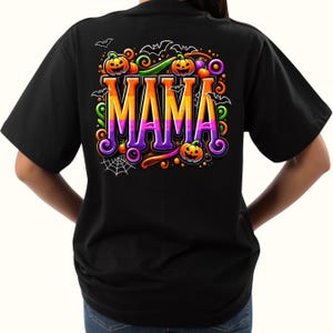 Puede incluir: Camiseta negra con un dise&ntilde;o colorido de Halloween. La palabra "MAMA" est&aacute; en letras grandes, con degradado naranja y morado, rodeada de calabazas, murci&eacute;lagos y una telara&ntilde;a. Un gr&aacute;fico festivo y de temporada.