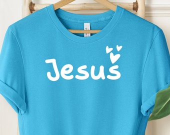 May include: A light blue t-shirt with the word "Jesus" in white lettering and small white hearts above the word.