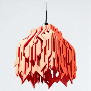 Puede incluir: Lámpara colgante moderna y geométrica en tonos naranja y melocotón. La pantalla tiene un diseño en capas y angular con una serie de cortes verticales e inclinados. Cuelga de un cable negro y un accesorio plateado.