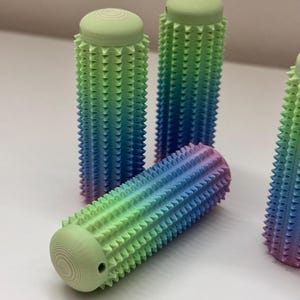 Peut inclure: Quatre poignées cylindriques texturées et colorées avec un dégradé de vert, bleu et violet. Les poignées ont une texture piquante.