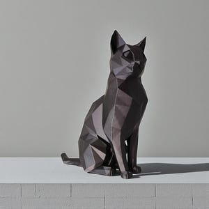 Puede incluir: Una escultura de gato geométrico gris oscuro. El gato está sentado con la cola extendida. La escultura tiene un diseño facetado, lo que le da una apariencia moderna y angular. El gato está sobre una superficie blanca.
