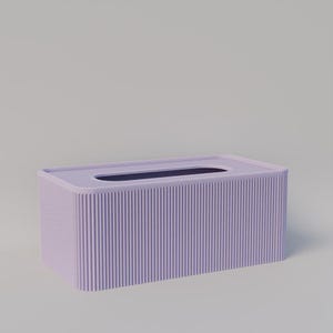 Op de afbeelding: Een rechthoekige tissuebox in een zachte lavendelkleur. De doos heeft een geribbeld, verticaal patroon aan de zijkanten en een rechthoekige opening aan de bovenkant. Het ontwerp is minimalistisch en modern.