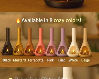 May include: A small, white ceramic fireplace with a flickering LED tea light and removable mini logs. The fireplace is available in 8 cosy colours: black, mustard, terracotta, pink, lilac, white, and beige. The text "Flickering LED tea light", "Eco-friendly", "3D printed design", "Removable mini logs" is displayed below the fireplace.