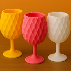 May include: Three stemmed glasses with a textured diamond pattern. The glasses are yellow, pink, and white.