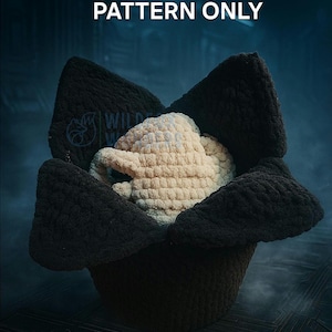 May include: A crocheted item, possibly a hat or decorative piece, in a dark color, cradling a lighter-colored, textured object. The text "PATTERN ONLY" is displayed prominently. The overall design suggests a craft project or handmade item.