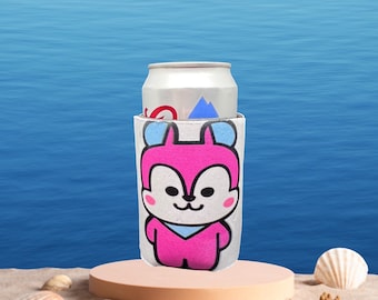 May include: A white can cooler with a pink cartoon animal wearing a blue scarf. The cooler is holding a silver can.