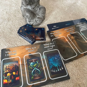 Puede incluir: Un mazo de cartas de oráculo con imágenes celestiales y la palabra "Insight" en la carta inferior. Una carta más grande muestra tres cartas más pequeñas con preguntas e ilustraciones, incluyendo una calavera, un reloj de arena y una escena estrellada. Una estatua gris en el fondo.