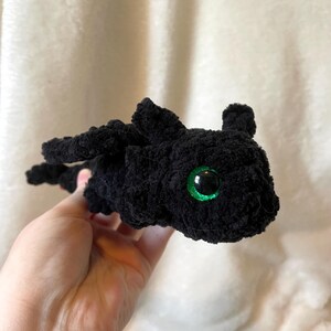 May include: Black crocheted plush toy dragon with green eyes.
