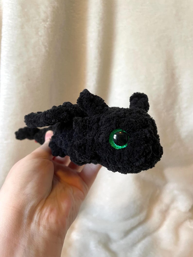 May include: Black crocheted plush toy dragon with green eyes.