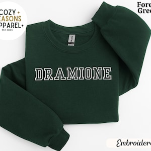 May include: Forest green sweatshirt with the text "DRAMIONE" embroidered in white with a black outline.