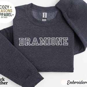 May include: Dark heather grey sweatshirt with the text "DRAMIONE" embroidered in white on the front.