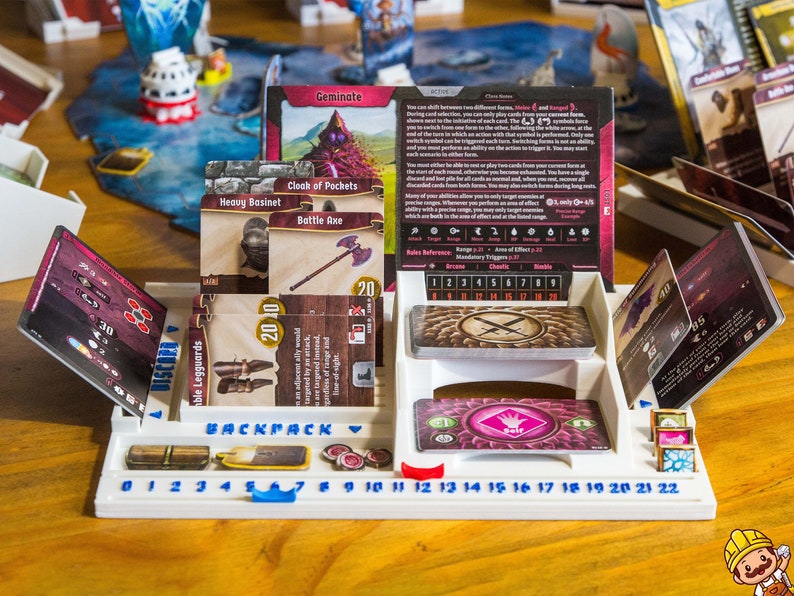 Pode incluir: Um organizador de jogos de tabuleiro em pl&aacute;stico branco com ranhuras para cartas, uma pista numerada de 0 a 22 e etiquetas incluindo Backpack e Discard. O organizador cont&eacute;m v&aacute;rias cartas de jogo com ilustra&ccedil;&otilde;es de um machado de batalha e grevas.