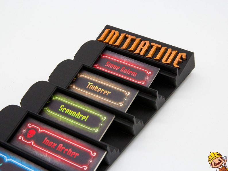 May include: A black plastic tabletop game organizer featuring the word INITIATIVE in orange lettering at the top. It contains four rectangular character cards labeled Stone Golem, Tinkerer, Scoundrel, and Inox Archer, each with distinct colored borders.