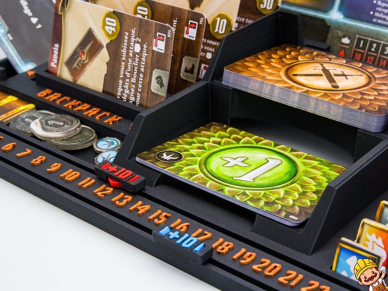 Pode incluir: Um organizador de jogos de tabuleiro preto impresso em 3D com uma se&ccedil;&atilde;o de mochila, compartimentos para cartas e uma trilha de contagem integrada com n&uacute;meros laranja de 6 a 22. Cont&eacute;m v&aacute;rias cartas de jogo, incluindo uma com um s&iacute;mbolo verde de mais um.