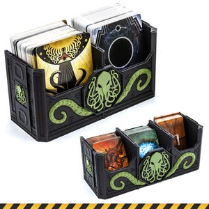 Könnte beinhalten: Zwei schwarze Kartenorganizer aus Kunststoff mit grünen Tentakelwesen-Emblemen und Reliefmustern. Der größere Organizer fasst zwei Kartenstapel, während der kleinere Organizer mit drei Fächern drei Kartenstapel mit verschiedenen Illustrationen enthält.