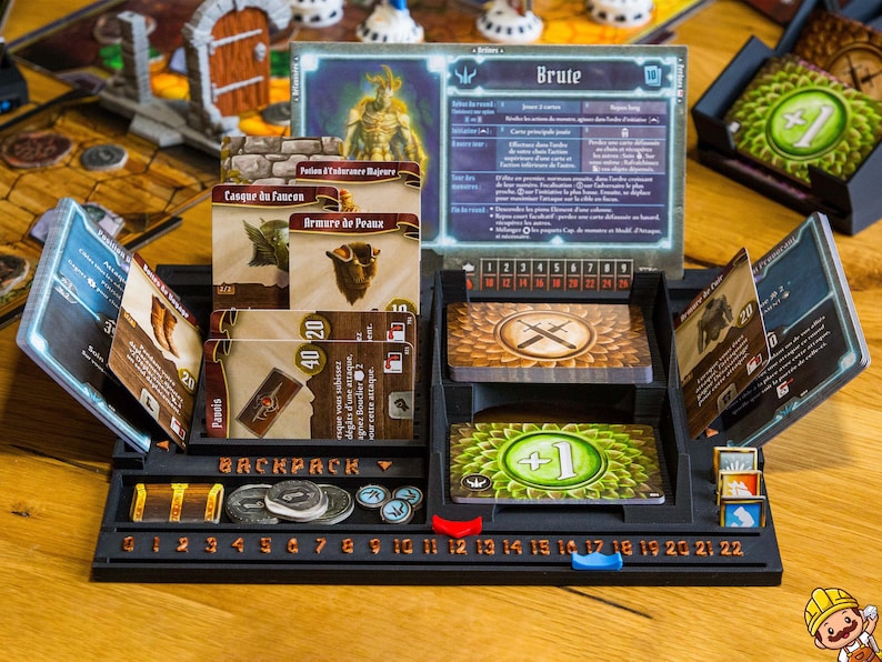Pode incluir: Um organizador de jogos de tabuleiro em pl&aacute;stico preto com um painel de personagem Brute, v&aacute;rias ranhuras para cartas com texto em franc&ecirc;s, uma &aacute;rea de armazenamento de mochila e uma pista numerada de 0 a 22 com marcadores.