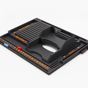 Pode incluir: Um organizador de jogos de tabuleiro preto impresso em 3D com etiquetas de texto laranja, incluindo DISCARD, BACKPACK e LOST. A bandeja inclui uma trilha numerada de 0 a 22, um slot central para cartas e marcadores deslizantes.