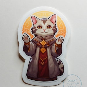 Può includere: Un adesivo raffigurante un gatto dei cartoni animati vestito con una veste con dettagli dorati, su uno sfondo di un alone dorato. Il gatto ha il pelo grigio e bianco, con le zampe alzate. L'adesivo ha un bordo bianco e un logo blu e bianco in basso a destra.