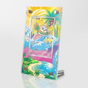 May include: A clear acrylic display frame holding a collectible trading card featuring a cartoon owl character, a yellow mouse-like creature, and a tropical beach scene with palm trees, a sailboat, and a bright sun, secured by four silver metal bolts.