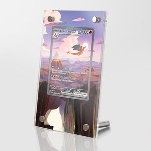 May include: A clear acrylic display stand with a Pokemon trading card featuring Charizard EX. The card has a purple, orange, and pink background with a picture of Charizard flying in the sky. The card has the text "Charizard EX" and "330" on it.