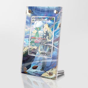 May include: A clear plastic display case with a blue, green, and white Pokemon card featuring a female character with long black hair and a green and white Pokemon character. The card is titled "Garchomp & Giratina GX" and has a number "130/149".
