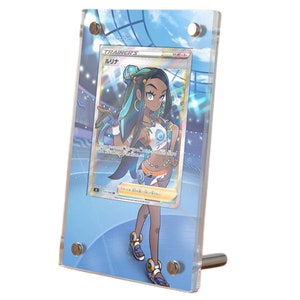 May include: A clear acrylic display case with a blue background and a silver stand. The case features a Pokemon trading card featuring a female character with blue hair and a blue and white outfit. The card text reads "TRAINER'S ルリナ".