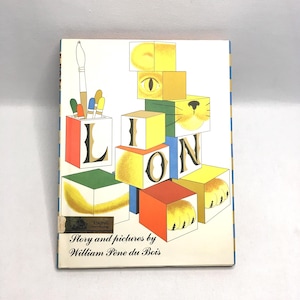 May include: A vintage children's book titled "Lion" by William Pène du Bois. The cover features colorful blocks spelling "LION" with lion-themed illustrations. A paintbrush and pencils are in a holder on the left.