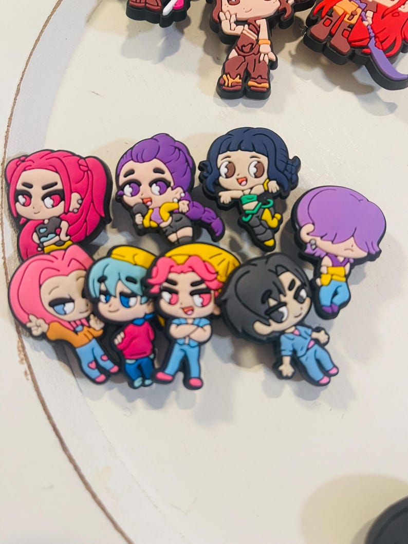 Pu&ograve; includere: Una collezione di ciondoli di personaggi dei cartoni animati colorati. I ciondoli presentano vari personaggi con diversi colori di capelli, abiti ed espressioni. I ciondoli sono realizzati in un materiale gommoso e sono probabilmente per scarpe o accessori.