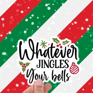 May include: A white sticker with the text "Whatever JINGLES Your bells" in black script, with a red and white striped background. The sticker has a Christmas ornament graphic and holly leaves. A hand holds the sticker.