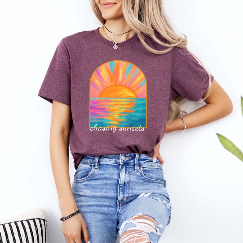 Puede incluir: Una camiseta color granate con un gr&aacute;fico de puesta de sol colorido y el texto "chasing sunsets" impreso en la parte delantera.