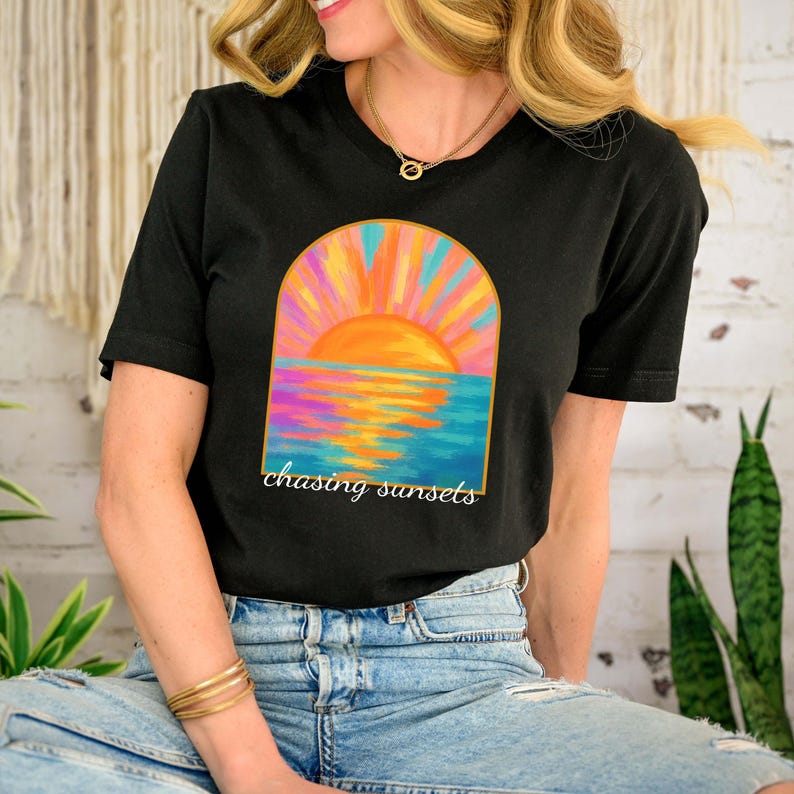 Puede incluir: Camiseta negra con un gr&aacute;fico de puesta de sol colorido y el texto "chasing sunsets" impreso en la parte delantera.