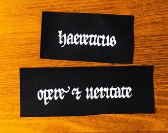 Ketzer. In Wort und Tat. Haereticus. Opere et veritate. Manuskript. Siebdruck Aufnäher.