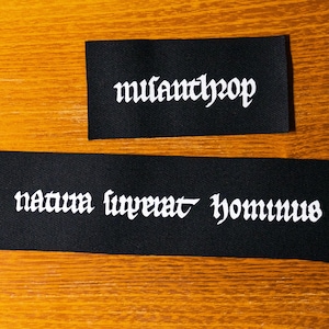 May include: Two black fabric patches with white text. The top patch says "mufanthrop" and the bottom patch says "natura lyperat hominus".