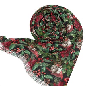 May include: A black scarf featuring a festive print of red poinsettias, green pine branches, brown pinecones, and bright red berries. The fabric has a soft texture and is finished with delicate, thin white fringe along the edges.