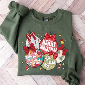 May include: Green Christmas sweatshirt with a design of colorful ornaments and the text "Merry Christmas" and "Ho Ho Ho".