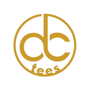 May include: A gold-colored logo featuring the letters "dc" inside a circle, with the word "tees" below. The design is simple and modern, set against a white background.