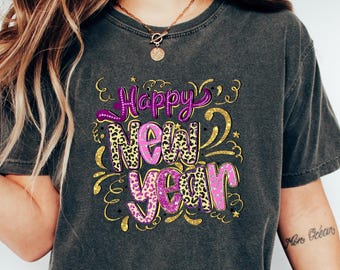 May include: Dark gray t-shirt with the words "Happy New Year" in a decorative design. The text features a mix of leopard print and gold accents. The shirt is a casual style.