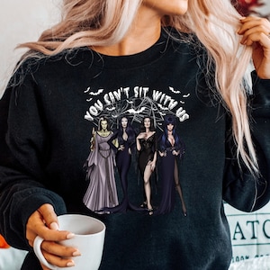 May include: Black sweatshirt with a graphic print of three women in black dresses and the text "You can't sit with us".