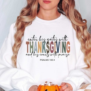 May include: White sweatshirt with the text "enter his gates with THANKSGIVING and his courts with praise" in colorful letters. The text is followed by "PSALMS 100:4".