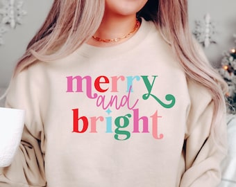 May include: A beige sweatshirt with the text "merry and bright" in colorful letters. The letters are in different colors, including red, pink, blue, and green.